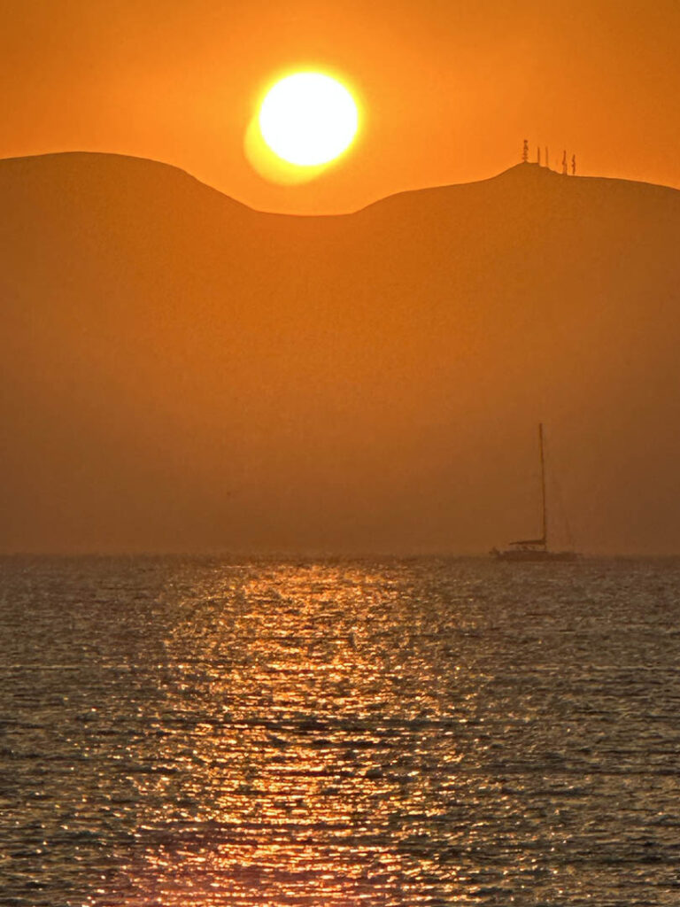 sunset over the sea with a yacht on the horizon