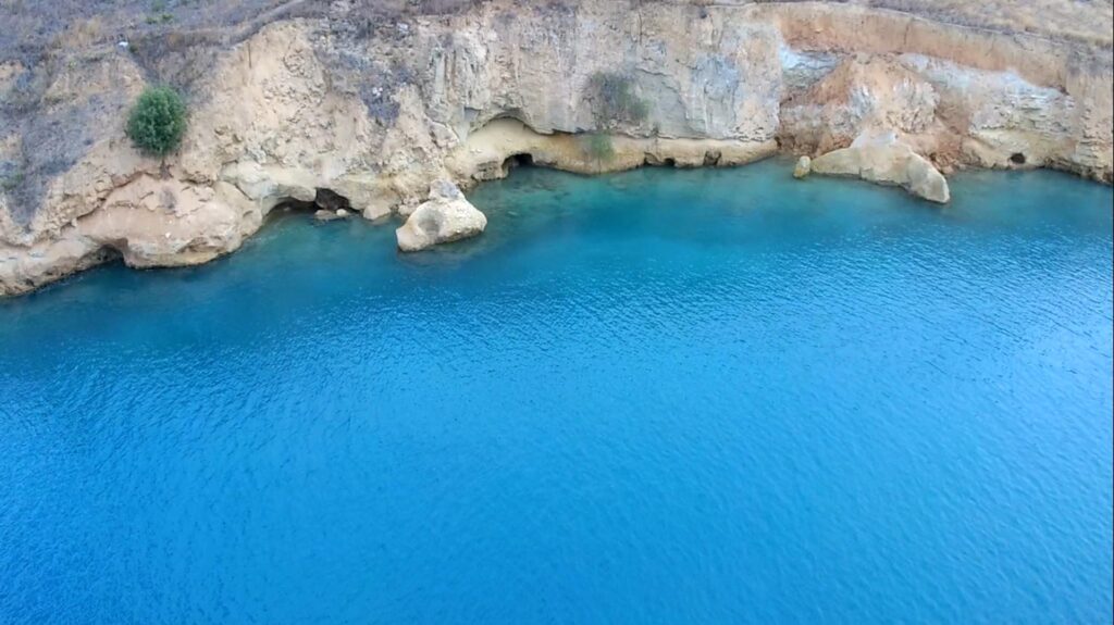 Rocky mountain forming caves on turquoise waters