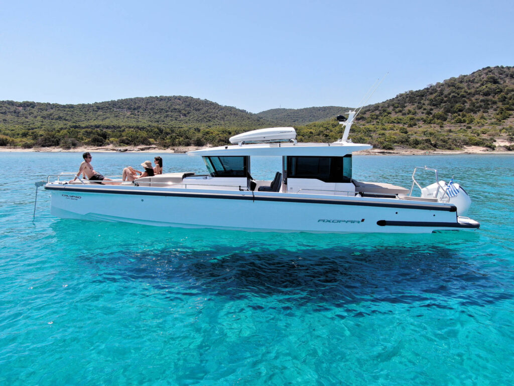 The Calypso yacht anchored in turquoise waters with green hills in the background