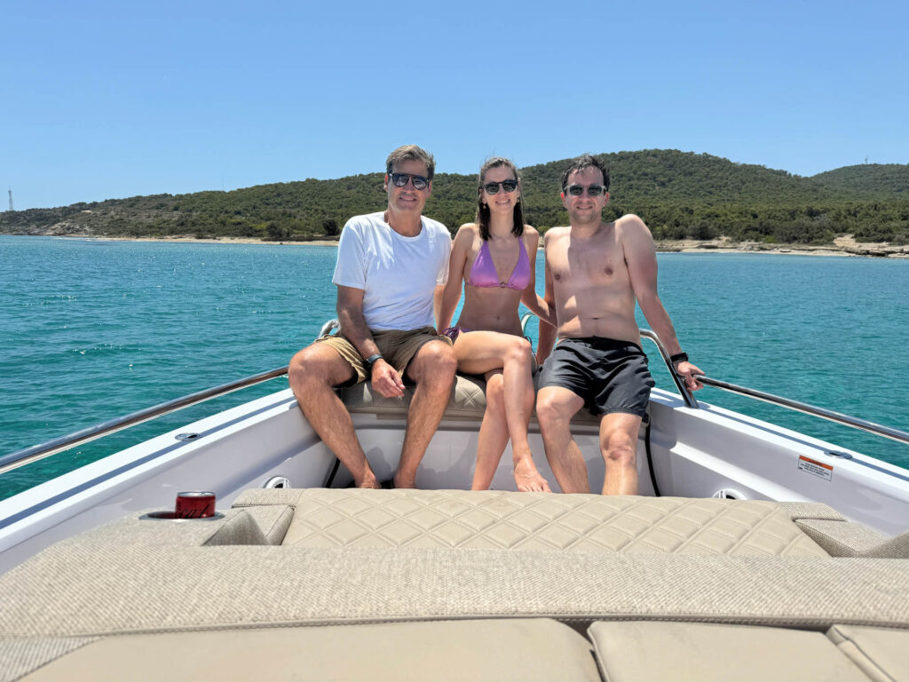 Passengers on the stern of the Calypso yacht with green hills on the background